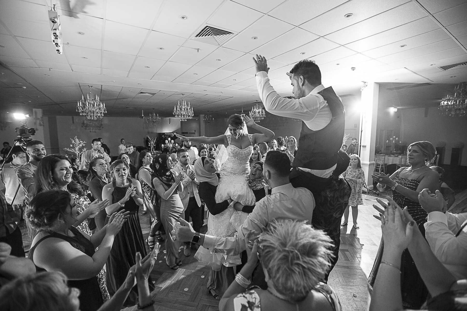 Wedding guests lifted up bride and groom celebrating during the dance on dance floor | Fantasie Photography