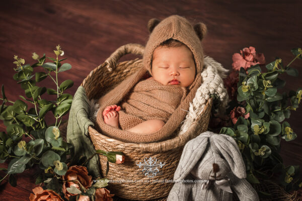 newborn baby sleeping in the basket and decorated with flowers